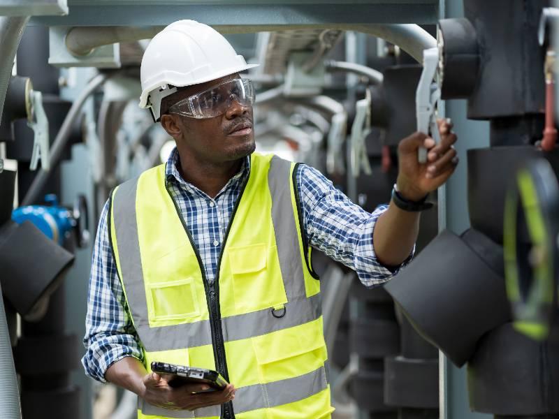 African American male engineer worker checks pipe network system at construction site
