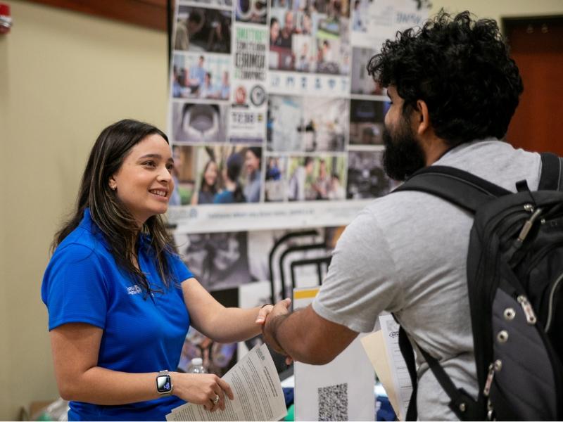 Student shaking hands with employer at a career fair.
